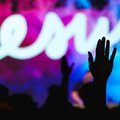 Viele Menschen mit erhobenen Menschen. Im Hintergrund ist auf einer Bühne das Wort Jesus zu lesen.
