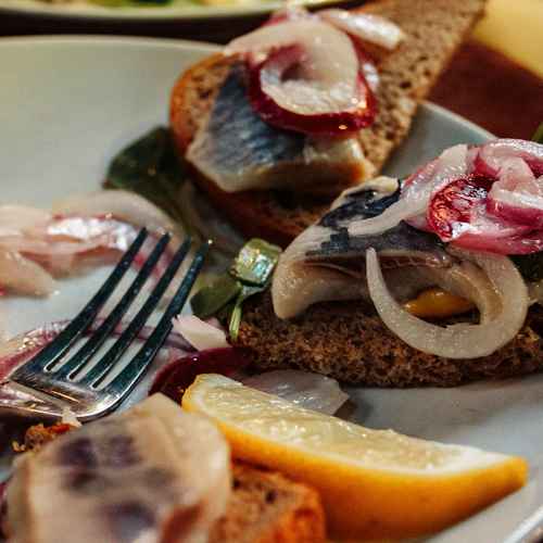 Ein Teller mit belegten Fischbrötchen ( Heringe, Zwiebeln)